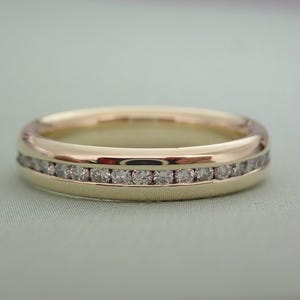May include: A gold band with a row of small diamonds set in a channel setting.