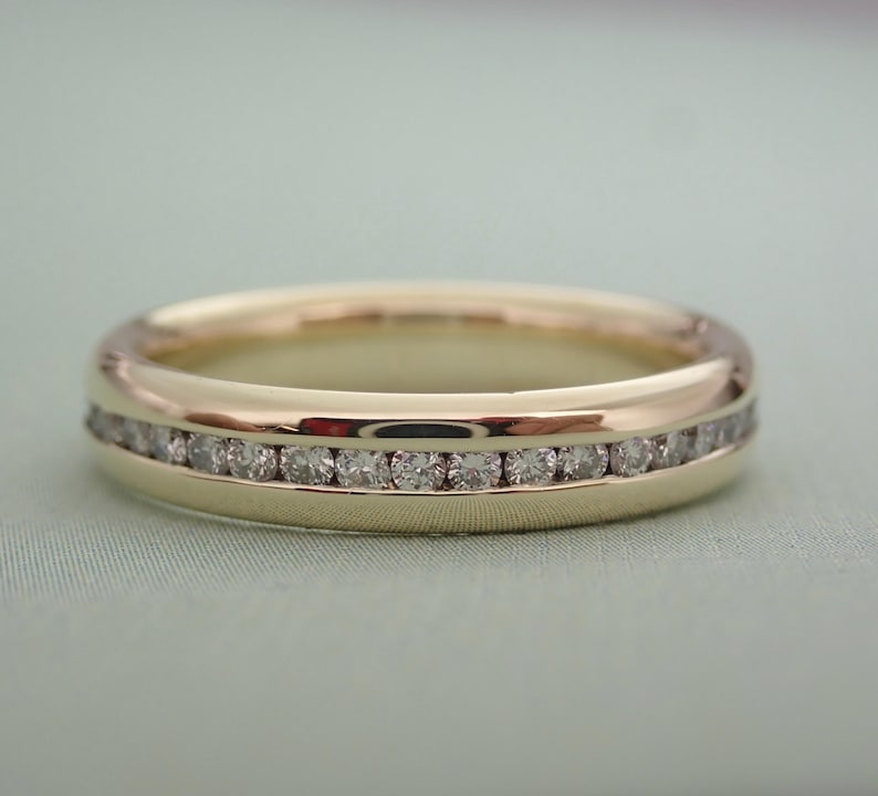 May include: A gold band with a row of small diamonds set in a channel setting.