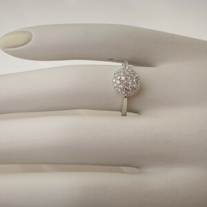 May include: A silver ring with a round, white diamond-encrusted center.