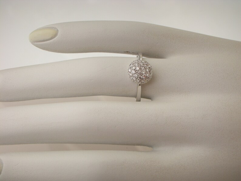 May include: A silver ring with a round, white diamond-encrusted center.
