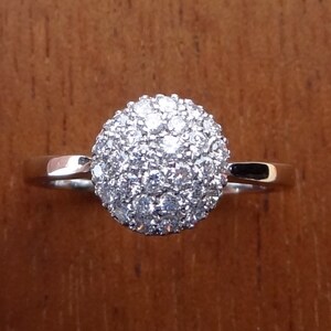 May include: A silver ring with a round, white diamond-studded center.