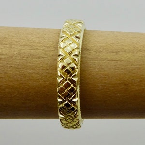 Puede incluir: Un anillo de banda de oro con un patr&oacute;n de diamante texturizado.