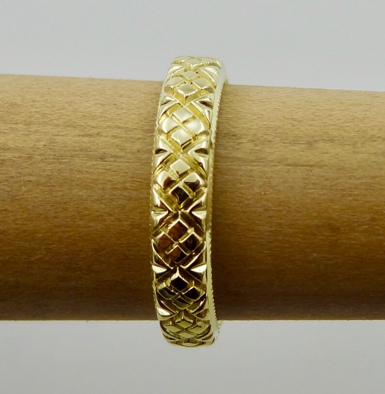 Puede incluir: Un anillo de banda de oro con un patr&oacute;n de diamante texturizado.