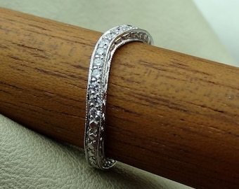May include: A delicate, silver band with a row of small, sparkling diamonds set in a decorative, intricate design.