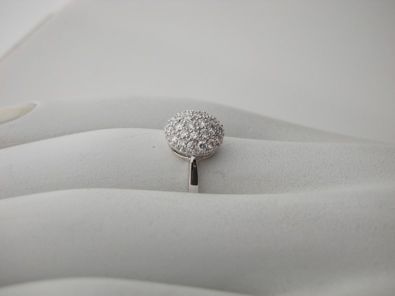 May include: A silver ring with a round, pave-set diamond top.