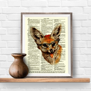 May include: Framed print featuring a whimsical fox illustration wearing glasses, set against a vintage dictionary page. The fox has orange and brown fur, with its tongue sticking out. The frame is a neutral color, and the print is displayed on a wooden shelf.