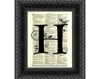 May include: Black framed art print featuring a large black letter "H" with decorative flourishes and a bird silhouette, set against a vintage dictionary page background. The frame has a textured, crackled finish.