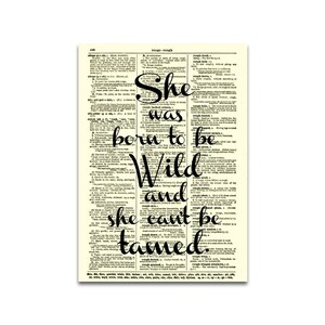May include: A framed print featuring a vintage dictionary page with the quote "She was born to be Wild and she can't be tamed" in black script. The background is a cream color.