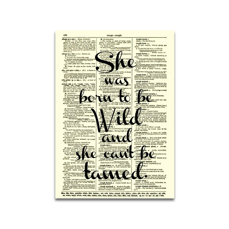 May include: A framed print featuring a vintage dictionary page with the quote "She was born to be Wild and she can't be tamed" in black script. The background is a cream color.