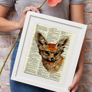 May include: A framed art print featuring a whimsical illustration of a fox wearing glasses and sticking out its tongue. The artwork is set against a vintage dictionary page background, with a white frame. The fox is depicted in shades of brown and orange.