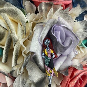 May include: A bouquet of artificial flowers in shades of white, pink, red, and green. A small figurine of Sally from the Nightmare Before Christmas is attached to the bouquet.