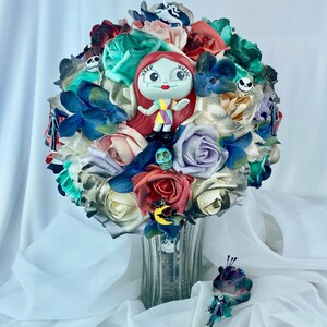May include: A bouquet of faux flowers in shades of white, cream, green, blue, and red. The bouquet features a small plastic figurine of Sally from the Nightmare Before Christmas, a skull, and a bat.