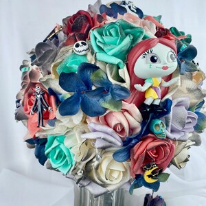 May include: A bouquet of artificial flowers in shades of red, white, blue, and green. The bouquet features a variety of flowers, including roses, hydrangeas, and other blooms. The bouquet is decorated with small figurines of characters from the movie "The Nightmare Before Christmas."