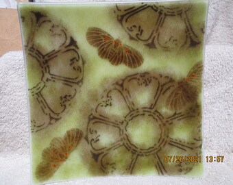 May include: Square glass plate with a green background and a brown design of stylized flowers and butterflies. The date 07/26/2021 and the time 13:57 are printed in the bottom right corner.