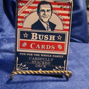 May include: A blue and red playing card deck box with a picture of George W. Bush on the front. The box says "Bush Cards" and "Fun for the whole family. Carefully stacked deck."