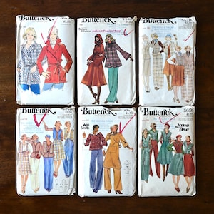 May include: Six vintage Butterick sewing pattern envelopes. The patterns feature illustrations of women's clothing designs, including coats, dresses, and pantsuits. The envelopes are in various colors and feature text such as "The Fashion One" and designer names.