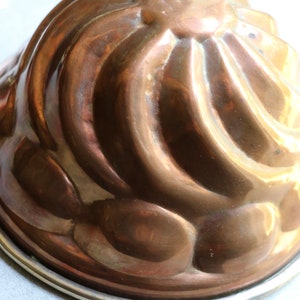 Puede incluir: Un molde de gelatina de cobre vintage con un dise&ntilde;o acanalado y un borde plateado.