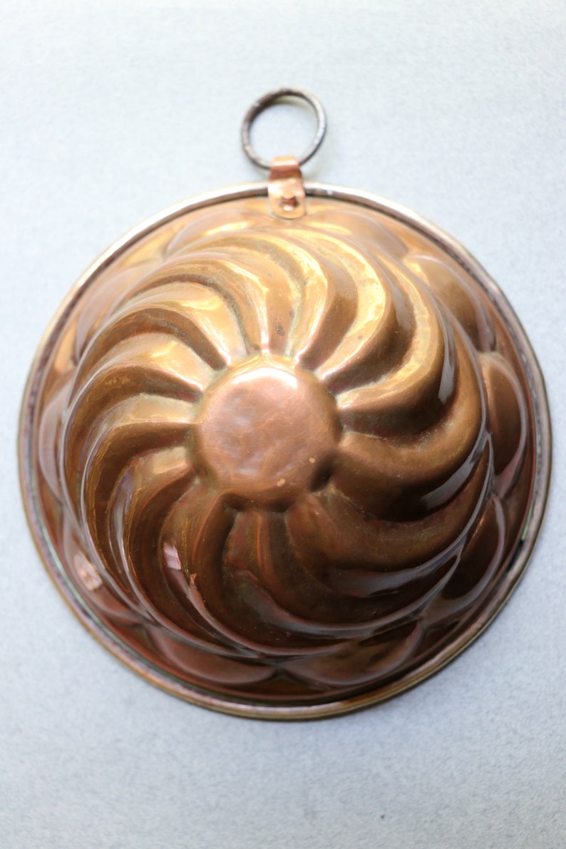 Puede incluir: Un molde para pastel de cobre vintage con un dise&ntilde;o de espiral. El molde tiene un lazo para colgar y est&aacute; en buen estado.