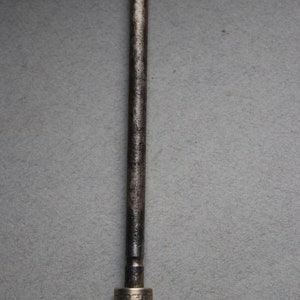 May include: A metal knife sharpener with a brown wooden handle. The handle has a silver band with a decorative pattern.