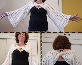 May include: White crocheted shrug with a criss-cross design in the front and a bow in the back. The shrug is shown being worn over a black top.