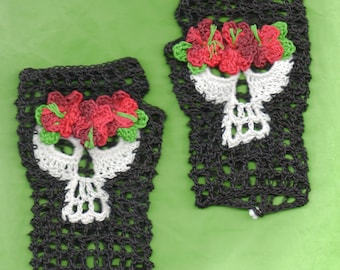 May include: A pair of black crochet fingerless gloves with white skull designs and red flower embellishments.
