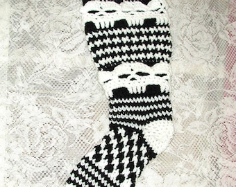May include: Black and white crocheted leg warmer with a skull pattern. The leg warmer is made with a houndstooth stitch.