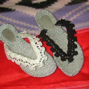 May include: Two pairs of silver flip-flops with decorative crocheted trim. One pair has white trim and the other has black trim.