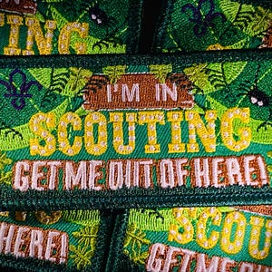 May include: Green embroidered patch with the text "I'm in Scouting Get me out of here!" in yellow and white lettering. The patch features a green background with a yellow and white flower design.