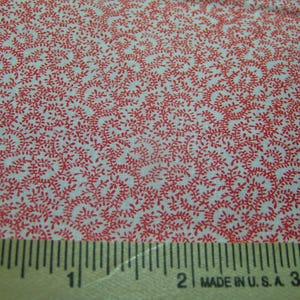 May include: Close-up of a fabric with a repeating pattern of red vines and leaves on a white background. A wooden ruler with black markings and the text "MADE IN U.S.A. 3" is at the bottom of the image.