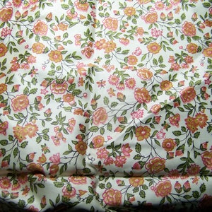 May include: White fabric with a repeating pattern of small pink and orange flowers with green leaves.