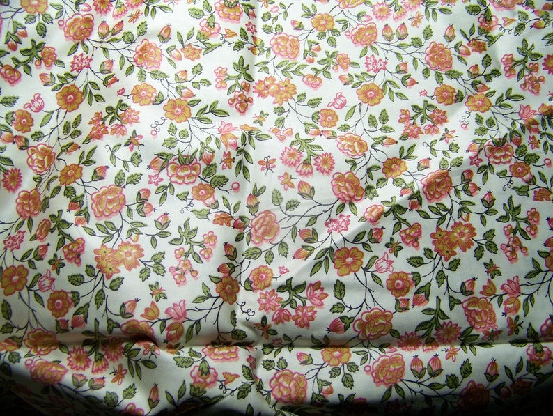 May include: White fabric with a repeating pattern of small pink and orange flowers with green leaves.