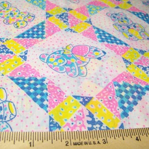 May include: A patchwork fabric featuring a repeating pattern of teddy bears and bunnies in pink, yellow, and blue. The fabric has a white background with small pink polka dots. The design includes geometric shapes and floral patterns.