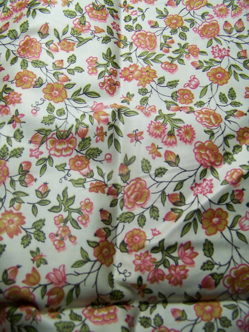 May include: A white fabric with a repeating pattern of pink and yellow flowers with green leaves. The fabric has a vintage feel.