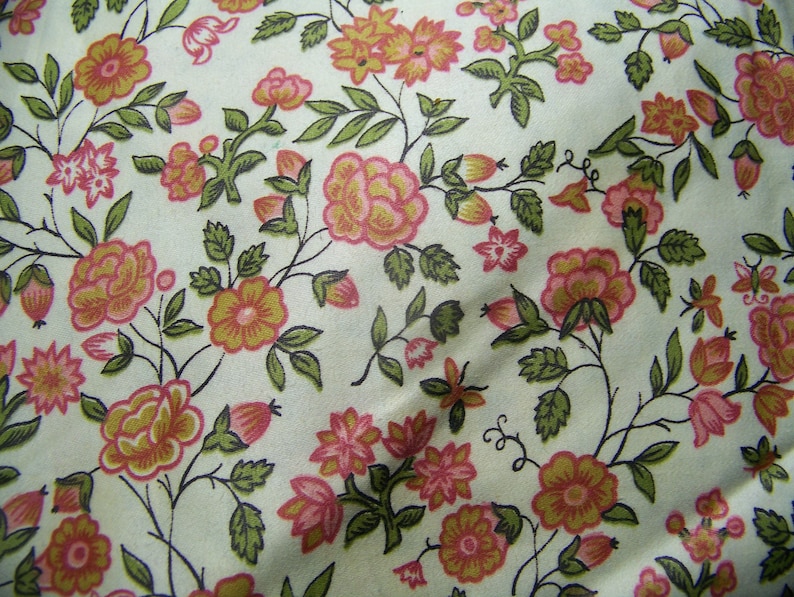 May include: A white fabric with a repeating pattern of pink and orange flowers with green leaves. The flowers are stylized and have a vintage look.