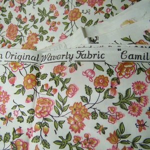 May include: A white fabric with a floral pattern in shades of pink, orange, and green. The fabric has a label that reads "An Original Waverly Fabric "Camille""