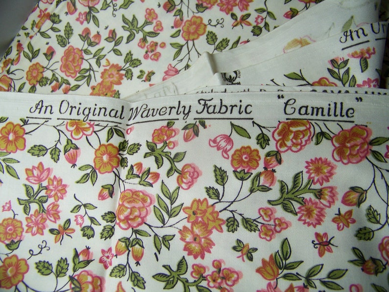 May include: A white fabric with a floral pattern in shades of pink, orange, and green. The fabric has a label that reads "An Original Waverly Fabric "Camille""
