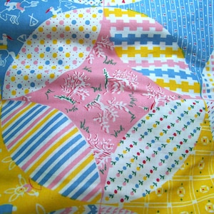 May include: A patchwork quilt with a variety of colorful patterns, including pink, blue, yellow, and white. The quilt is made of different fabrics with polka dots, stripes, and floral designs.