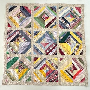 May include: A patchwork quilt with nine square blocks, each featuring a unique design of colorful fabric strips. The quilt's border has a floral pattern. The fabrics include red, yellow, blue, green, and patterned textiles.
