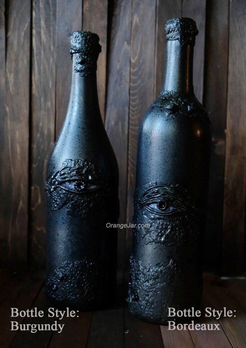 May include: Two black glass bottles with a textured surface and an eye design. The bottle on the left is labeled "Bottle Style: Burgundy" and the bottle on the right is labeled "Bottle Style: Bordeaux".