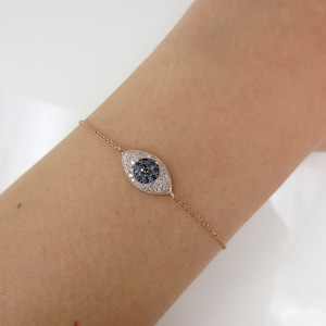 May include: A rose gold bracelet featuring a diamond and sapphire evil eye charm.