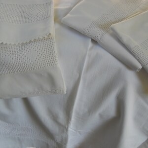 May include: A stack of white cotton pillowcases with delicate crocheted lace trim. The pillowcases are folded and arranged on a white surface.