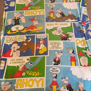 May include: A colorful fabric featuring a repeating pattern of Popeye the Sailor Man comic strips. The fabric features Popeye, Olive Oyl, and Bluto in various scenes, including Popeye eating spinach, Popeye and Olive Oyl in a boat, and Popeye fighting Bluto. The fabric is blue, green, yellow, red, and black.