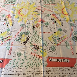 May include: A white rectangular textile featuring a repeating pattern of yellow suns and illustrations of California landmarks including the Golden Gate Bridge, Hollywood, and San Diego. The fabric includes text such as Mexico, Salton Sea, and a handwritten letter.