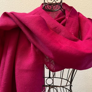 May include: A deep crimson red shawl made of soft fabric, draped over a black metal display stand.
