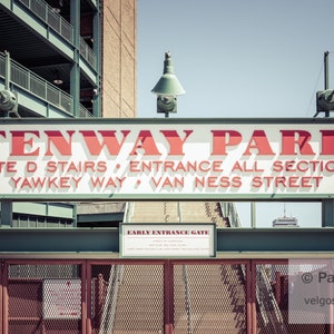 May include: A white sign with red lettering reads "Fenway Park" and lists the entrance information: "Gate D Stairs, Entrance All Sections, Yawkey Way, Van Ness Street".