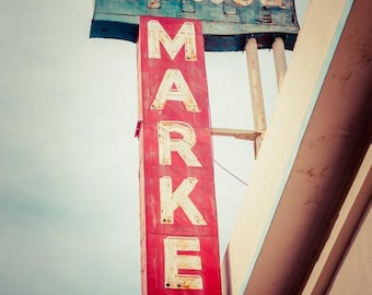 May include: Vintage sign for Balboa Market. The sign is red with white lettering spelling out MARKET vertically. The top of the sign reads Balboa in a cursive font. The sign is mounted on a building.