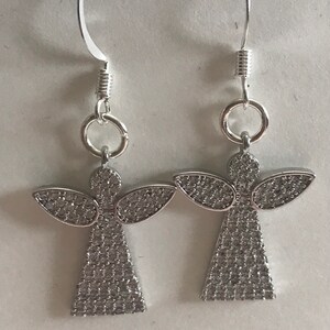 May include: A pair of silver angel earrings with clear crystal accents. The earrings have a hook closure.