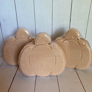 May include: Three beige pumpkin-shaped bath bombs wrapped in clear plastic.