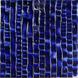 Peut inclure: Carreau de céramique carré, texturé, avec un glaçage bleu profond et brillant. La surface présente des crêtes et des rainures verticales et inégales, créant un motif tactile et visuellement intéressant. Le design évoque la profondeur et la texture organique.