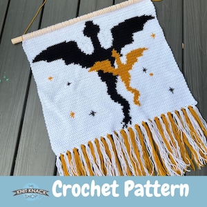 May include: Crochet pattern for a wall hanging featuring a black and gold dragon with stars on a white background. The dragon has a long tail and wings. The wall hanging has a fringe of gold and white yarn.